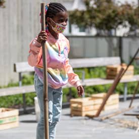 Girl stands with tall stick