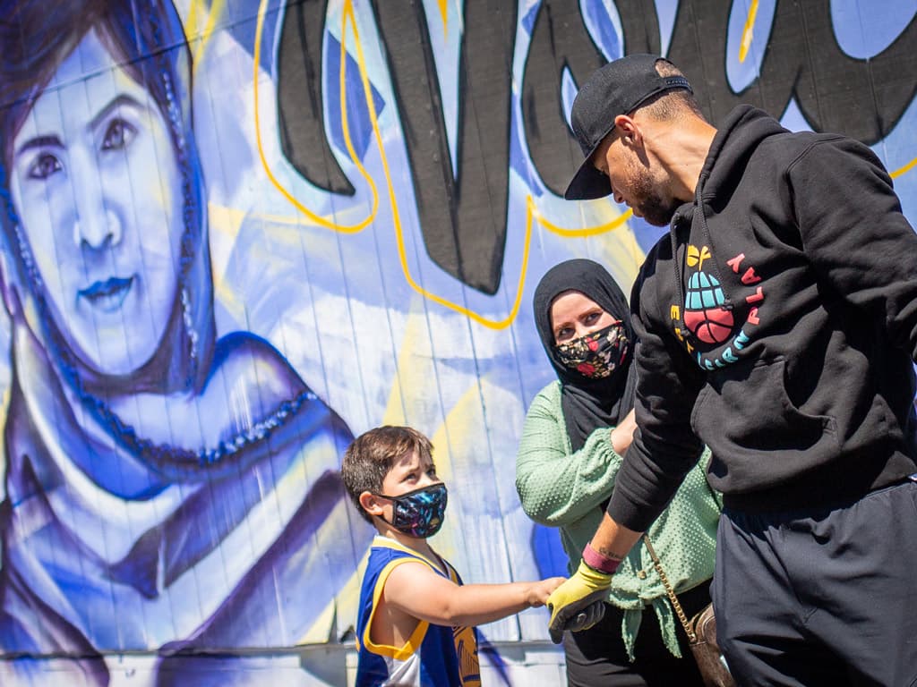 Stephen Curry and kid fistbump during Franklin Elementary playspace build